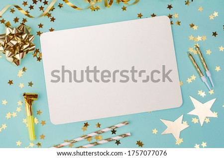Blue pastel background with a golden star, the golden bows and the star confetti on  table top view. Flat lay golden decoration composition for birthday, christmas or wedding.