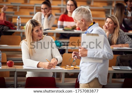 Elderly professor answering student's questions in amphitheater