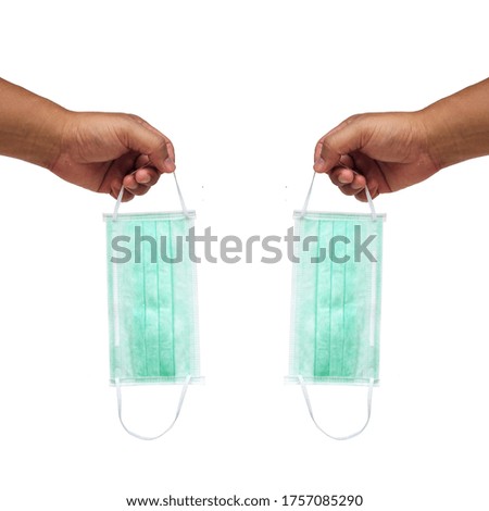 Left and right hands holding medical face masks isolated on white background.