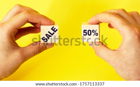 Man holds cubes with the text sale and 50 on a yellow background