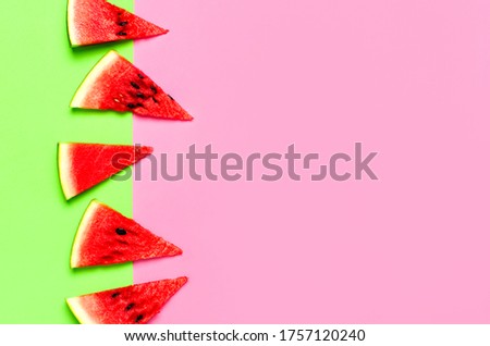 Creative summer food concept. Watermelon pattern. Juicy slices of ripe red watermelon on multicolored pink and green background. Flat lay, top view, copy space. Summer berry, healthy