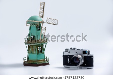 Tourism and travel concept - Vintage camera and tin vintage windmill model on a white background 