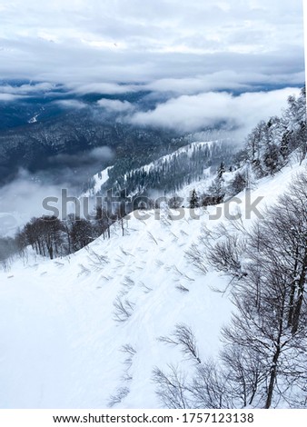 Snowy mountains, blue sky with clouds. Fog