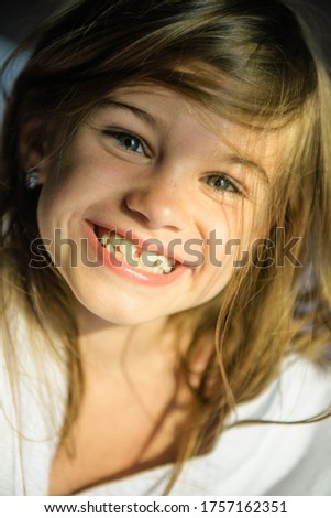 ute little girl is smiling funny at the camera. The gap between the teeth. Funny and beautiful smile. Beloved daughter. Crooked baby teeth in a funny girl Royalty-Free Stock Photo #1757162351