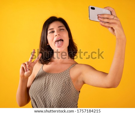 pretty girl takes a selfie with the phone, yellow background