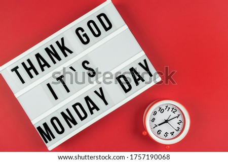 Text THANKS GOD IT IS MONDAY DAY on lightbox on red background with alarm clock. Copyspace for text