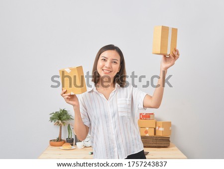 Asian woman hold package box order, working at home office. Online marketing delivery, startup SME entrepreneur or freelance concept