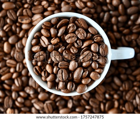 Natural coffee background, white cup steeped of coffee beans.