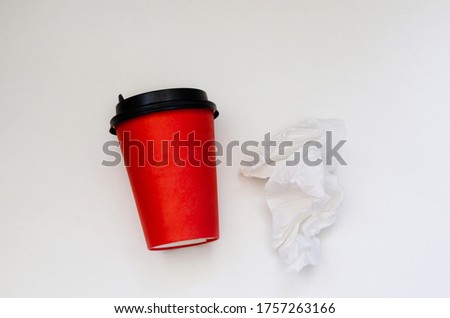 paper red cup of coffee and a crumpled napkin on white background