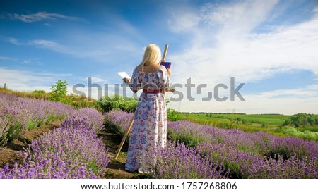 Beautiful young woman drawing picture on lavender field at morning.