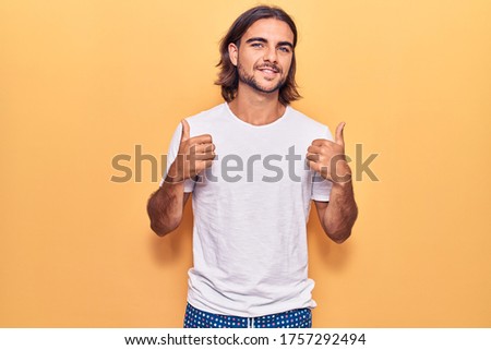 Young handsome man wearing casual clothes success sign doing positive gesture with hand, thumbs up smiling and happy. cheerful expression and winner gesture. 