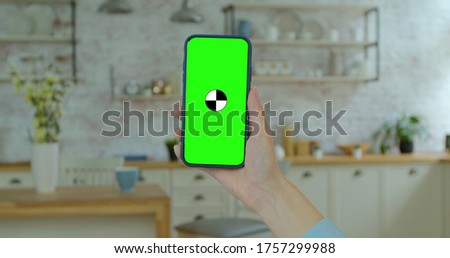 Pretty girl making video call on smartphone. Woman at Home Uses Green Mock-up Screen Smartphone. Watching Video Content, Blogs.