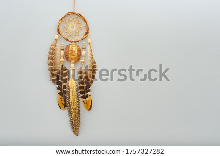 Closeup details modern dreamcatcher with painted golden feathers on gray background