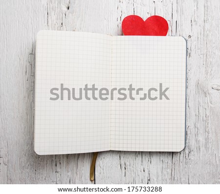 Blank notepad with red heart on wood background