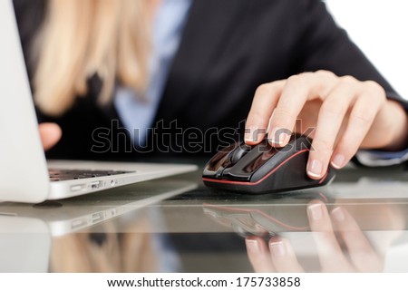 Close-up of working businesswoman. Woman's hands touching computer mouse and keys of silver opened laptop, against white background.