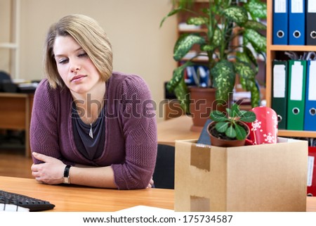 Dismissal - frustrated woman at a desk with a box with things