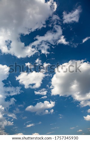 Bright white cumulus clouds in the clear blue sky on a sunny day. Vertical orientation.