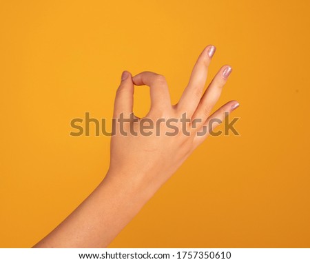 woman hand making ok gesture, on yellow background