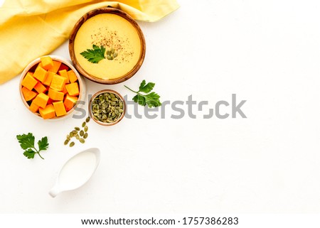 Pumpkin soup on white table top view. Ingredients in bowls. Copy space