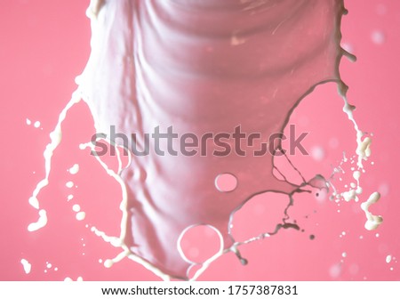 Splashes of white milk on a pink background. Drink