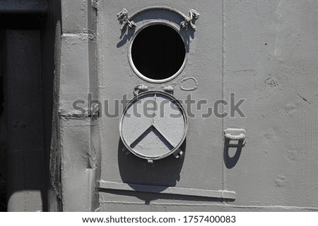 The porthole of the old warship is closed with a steel cover
