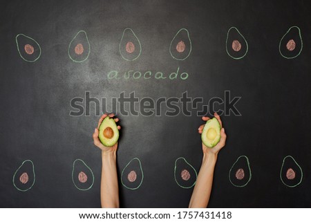 Avocado in the hand. Drawing on a black chalkboard