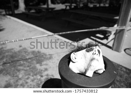 Halloween Mask in an Ash Tray with Caution Tape in the Background (Black and White)