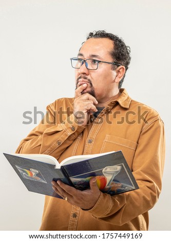 expression and people concept - Thinking man with a book over gray background. Adult over 40 years of age.