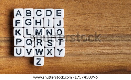 Set of 26 small white beads letters - whole alphabet - on wooden table, view from above, space for text right side Royalty-Free Stock Photo #1757450996