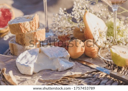 summer picnic on the coastline of sea. composition with rose wine in glasses, camamber cheese, apricots, melon, hamon and baguette. 
