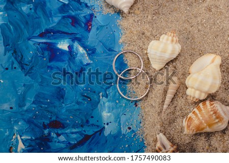 nautical composition blue background ocean background wedding background sand beach shells wedding rings on sand