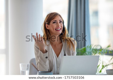 Smiling woman using laptop while talking to customer on phone. Consulting corporate client in conversation with customer using computer on desk. Service desk consultant talking in a call center