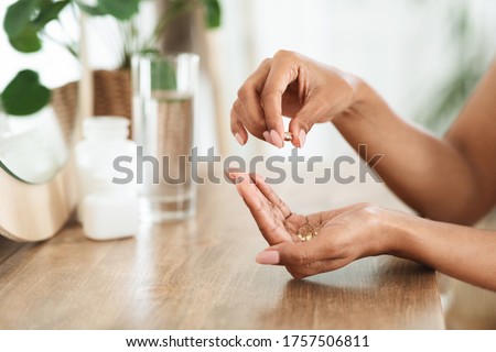 Unrecognizable African Woman Taking Beauty Supplements For Glowing Skin, Holding Omega-3 Fish Oil Capsules In Hands, Side View Royalty-Free Stock Photo #1757506811