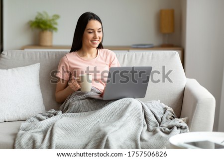 Weekend Leisure. Woman With Laptop Watching Movie Having Coffee Relaxing Sitting Covered With Blanket On Couch At Home Royalty-Free Stock Photo #1757506826