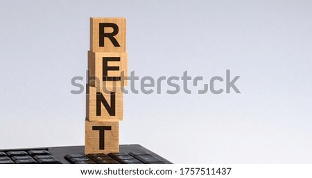 Text of RENT on wooden cubes. The cubes are located on the keyboard.