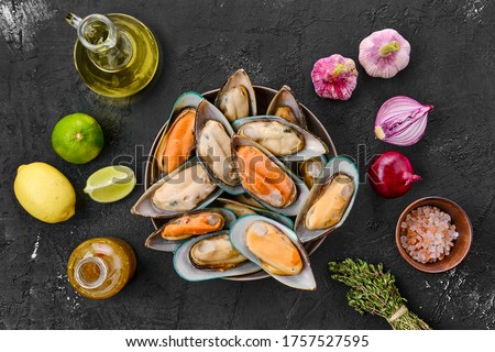 Raw large mussels in half shell with spice and herbs on black background Royalty-Free Stock Photo #1757527595