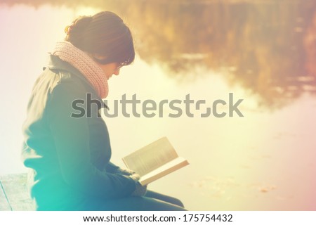 Woman reading a book at the lake