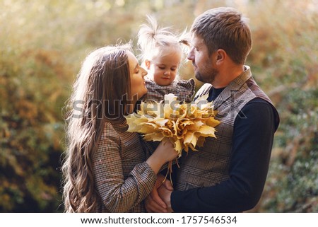 Family in a autumn park. Woman in a brown dress. Cute little girl with parents