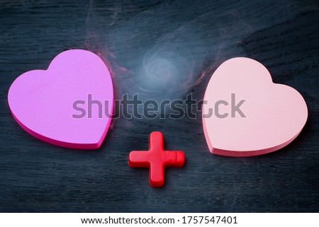 Two blank heart shaped stickers with plus sign. Smoke as a symbol of passion. Background