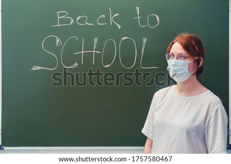Woman teacher stands next to the text "Back to schoo" on the school blackboard. Problems of school education and Internet lessons in the coronavirus pandemic