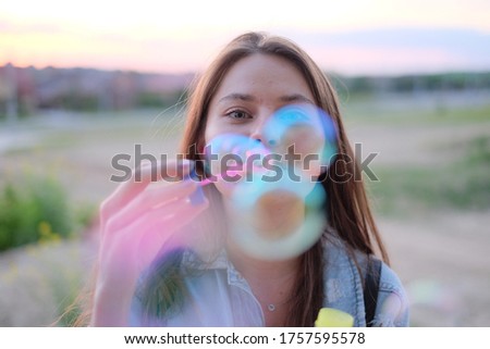 a young beauty blows soap bubbles at sunset, smiles and enjoys life