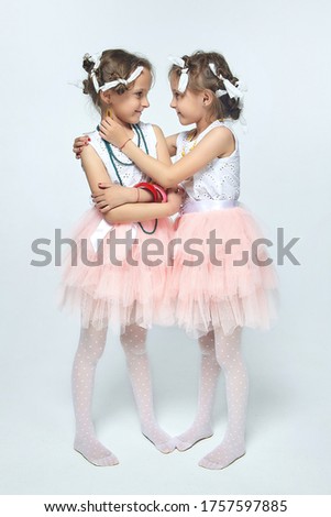 two little girls play with their mother's makeup. they pose and try to be adults.Studio, white back