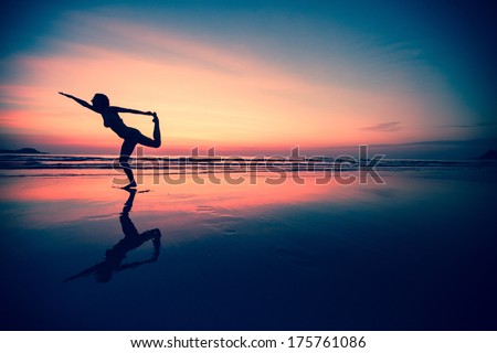 Silhouette of a woman practicing yoga on the beach at sunset.