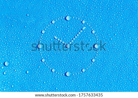 Drops of water in the form of a dial are located on a wet blue background. Abstract blue background. Time is water.