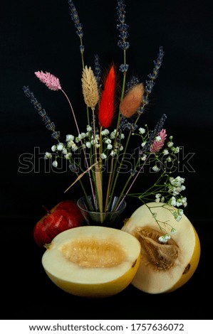 art photo ripe melon cut in half with apple and flowers on a black background