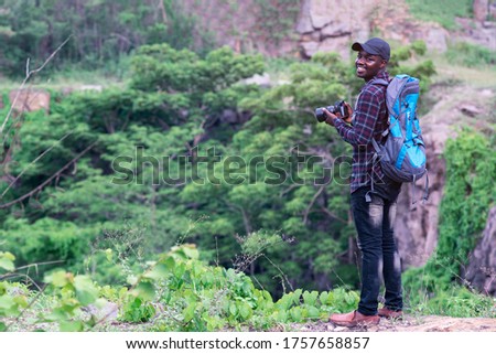 African man traveler holding camera with backpack