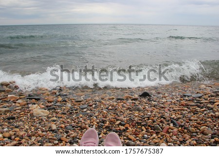 perspective on sneakers on the background of waves of Lake Baikal and a stone beach