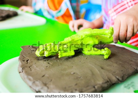 Children pressing animal pictures into clay.
