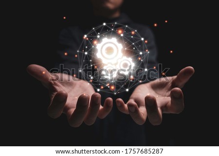 Two hand hold group of virtual cog gears wheel with connection and black background. It is symbol of association connection in business strategy. Royalty-Free Stock Photo #1757685287