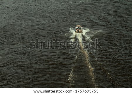 Top view of the river with a fast-moving motorboat with tourists in a nature reserve. Fishermen sail on the ship for the catch. Beautiful pretty landscape. Stock photo